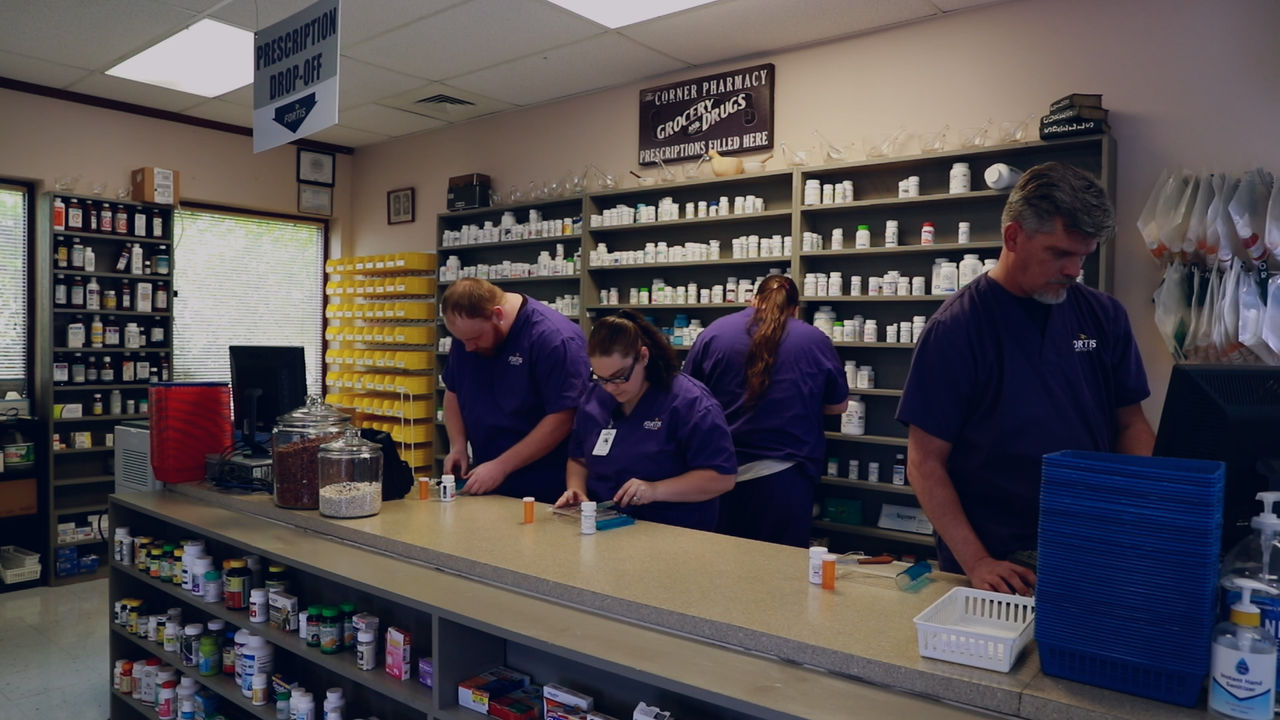 Pharmacy staff preparing prescriptions behind counter